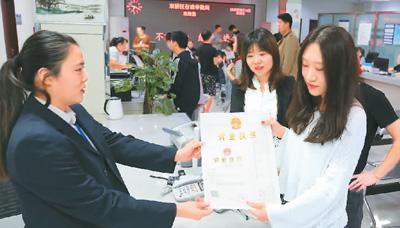 河北省承德市網(wǎng)絡(luò)代購(gòu)經(jīng)營(yíng)者陳晨(右)從工作人員手中接過帶有統(tǒng)一社會(huì)信用代碼的營(yíng)業(yè)執(zhí)照。 劉環(huán)宇攝(人民圖片)